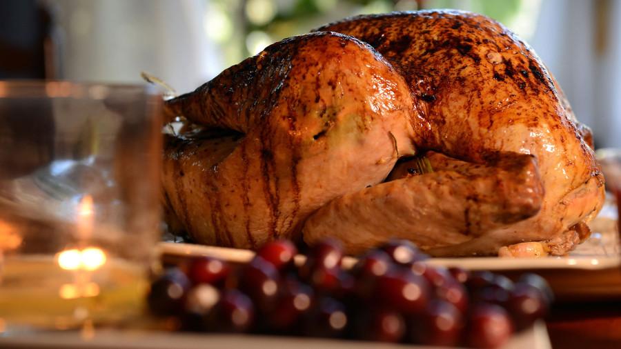 A turkey sits on a table ready for a family to feast upon it. 