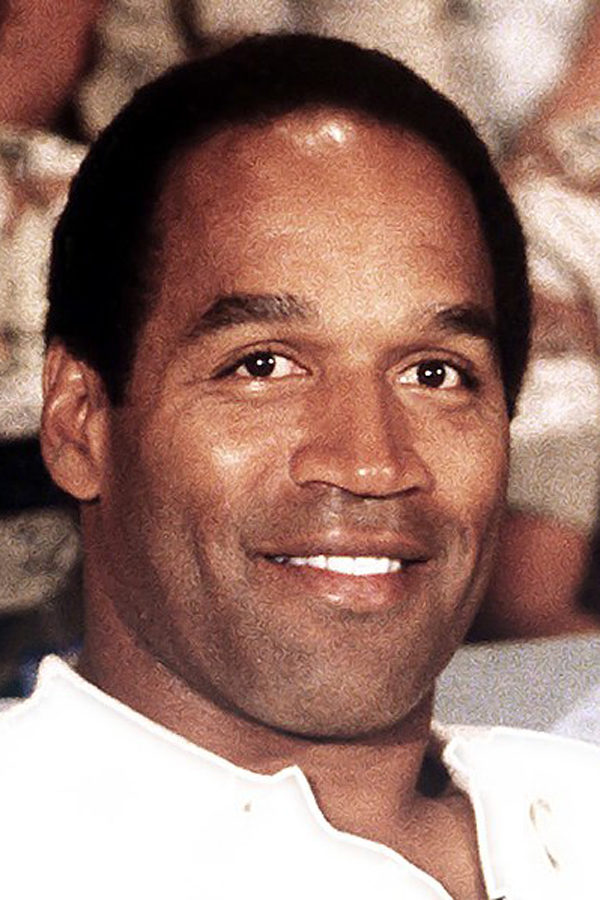 Former professional football player O. J. Simpson sits with a group of servicemen to watch a Thanksgiving Day football game. Simpson was released from prison in early October on parole.